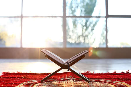 Rehal with open Koran on Muslim prayer mat indoorsの写真素材