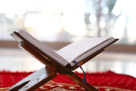 Rehal with open Koran on Muslim prayer mat indoorsの写真素材