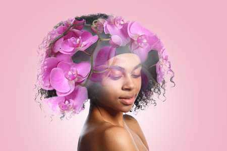 Portrait of young African-American woman with beautiful orchid flowers on color backgroundの写真素材