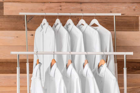 Racks with clothes after dry-cleaning on wooden backgroundの写真素材