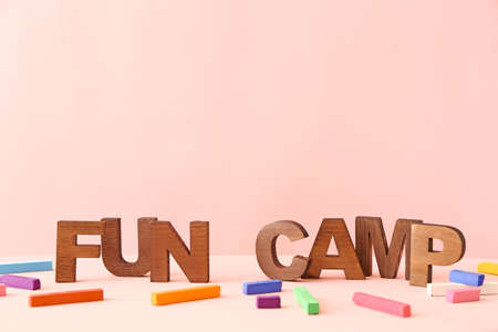 Crayons and text FUN CAMP on table against color background