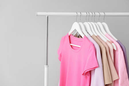 Rack with clothes after dry-cleaning on light background