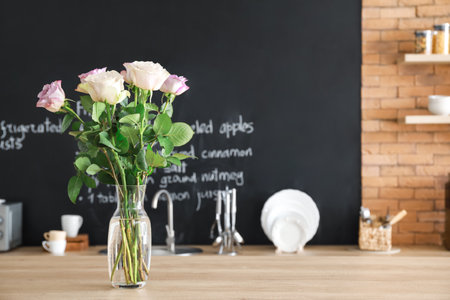 Vase with beautiful flowers on table in kitchenの写真素材