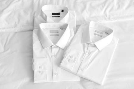 Folded shirts after dry-cleaning on bedの写真素材