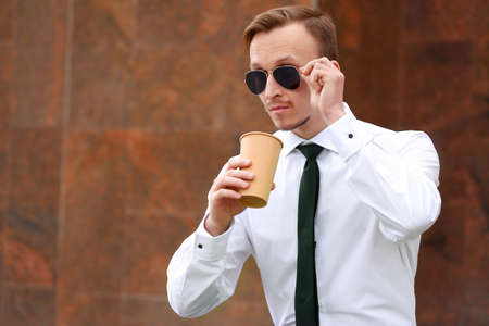 Handsome businessman drinking coffee outdoorsの写真素材