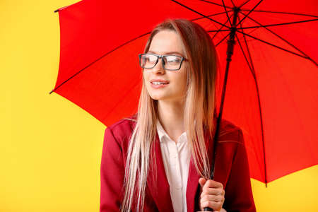 Beautiful businesswoman with umbrella on color backgroundの写真素材