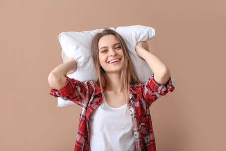 Young woman with pillow on color backgroundの写真素材