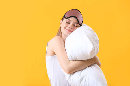 Young woman with pillow and sleep mask on color backgroundの写真素材