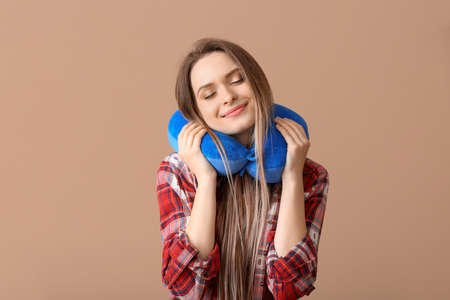 Young woman with travel pillow on color backgroundの写真素材