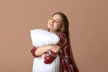 Young woman with pillow on color backgroundの写真素材