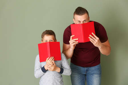 Portrait of father and son with books on color backgroundの写真素材