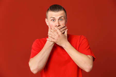 Shocked young man on color backgroundの写真素材