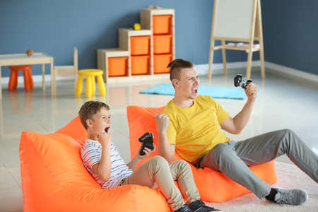 Portrait of father and son playing video game at home