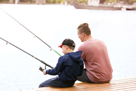 Father and son fishing together on river