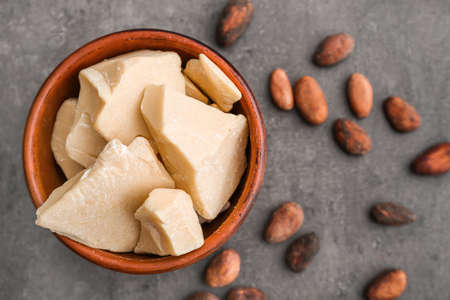 Bowl with cocoa butter on gray background