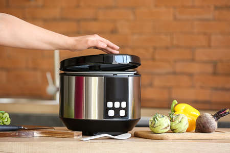 Woman using modern multi cooker in kitchen
