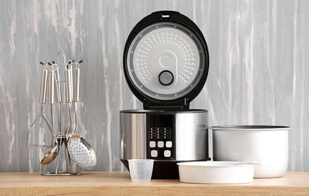 Modern multi cooker with accessories on kitchen table
