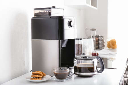 Modern coffee machine and hot beverage on kitchen table