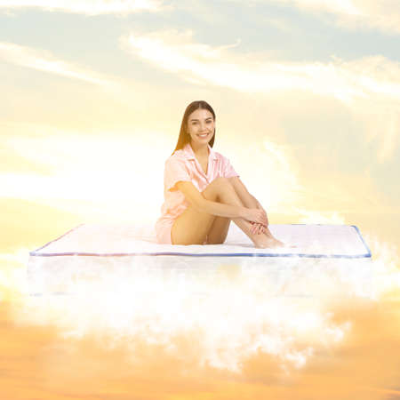 Young woman sitting on mattress soft as cloudsの写真素材