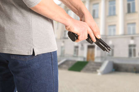 Man with gun near school outdoorsの写真素材