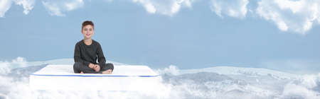 Little boy sitting on mattress soft as cloudsの写真素材