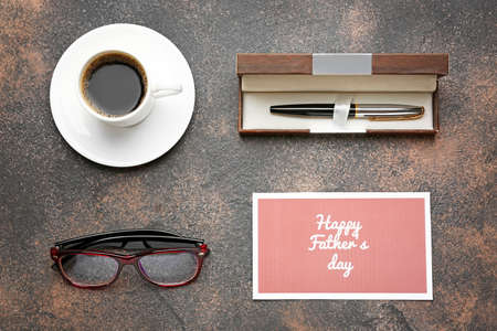 Cup of coffee, glasses, pen and card with text HAPPY FATHER'S DAY on grunge background