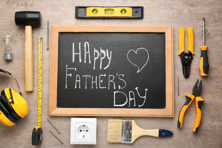 Different tools and chalkboard with text Happy Father's Day on wooden background