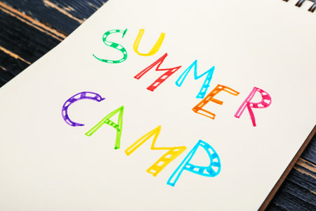 Notebook with words SUMMER CAMP on wooden background, closeupの写真素材