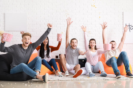Friends watching sports on TV at homeの写真素材