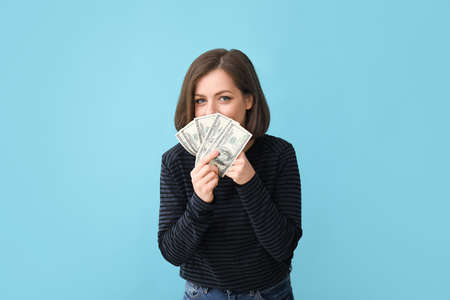 Beautiful young woman with money on color background