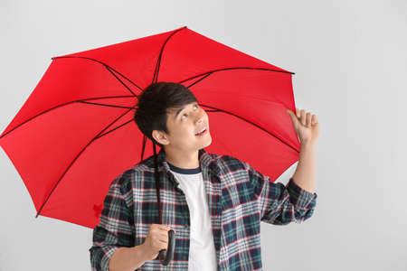 Handsome Asian man with umbrella on white backgroundの写真素材