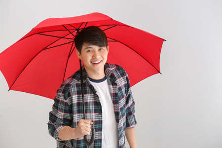 Handsome Asian man with umbrella on white backgroundの写真素材