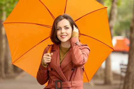 Beautiful young woman with umbrella outdoors on rainy dayの写真素材