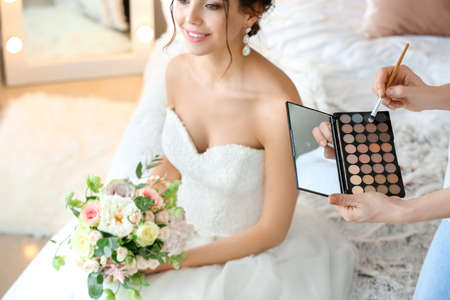 Professional makeup artist working with young bride at homeの写真素材