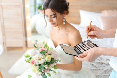 Professional makeup artist working with young bride at homeの写真素材