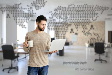 Male programmer with laptop and cup of coffee in office