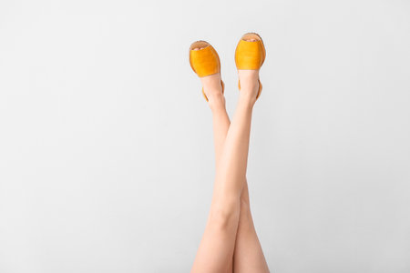 Legs of young woman in stylish shoes on light backgroundの写真素材