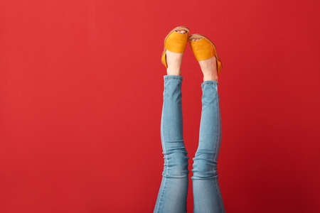 Legs of young woman in stylish shoes on color backgroundの写真素材