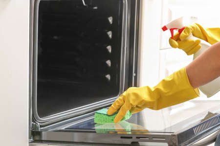 Woman cleaning oven at home