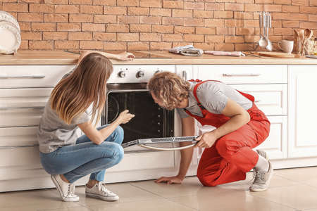 Worker repairing oven in kitchenの写真素材