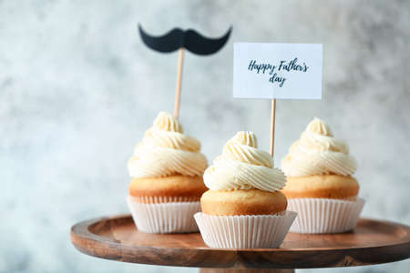 Stand with tasty cupcakes for Father's Day on gray backgroundの写真素材
