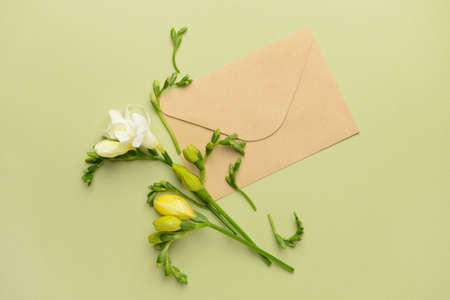 Beautiful freesia flowers and envelope on color backgroundの写真素材