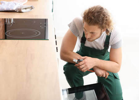 Worker repairing oven in kitchenの写真素材