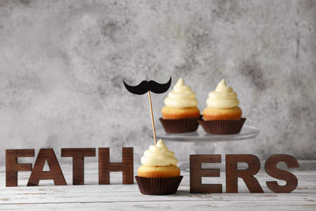 Tasty cupcakes for Father's Day on white wooden table