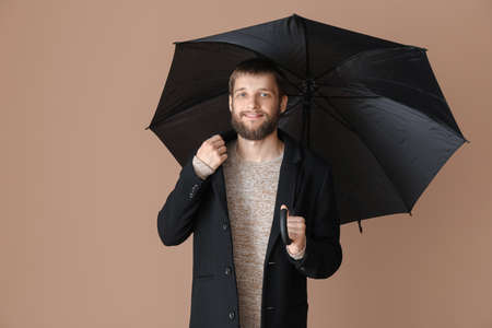 Handsome man with umbrella on color backgroundの写真素材