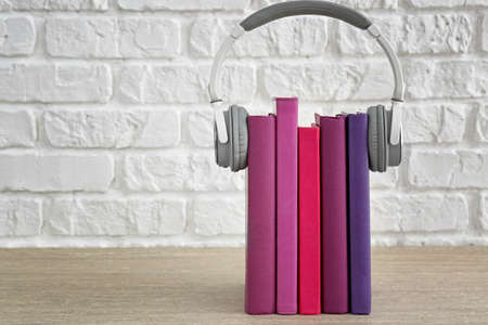 Books and modern headphones on table. Concept of audiobookの写真素材
