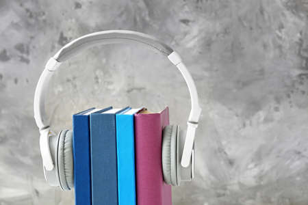 Books and modern headphones on gray background. Concept of audiobookの写真素材