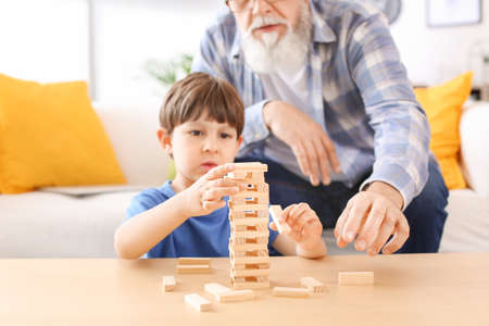 Cute little boy playing with grandfather at homeの写真素材