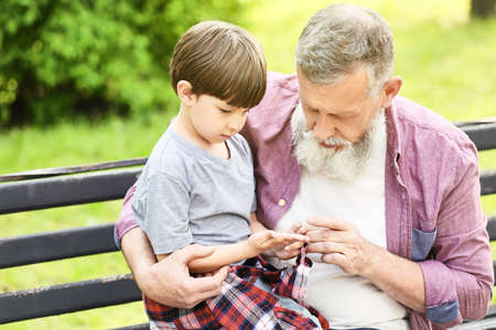 Cute little boy and his grandfather playing in park