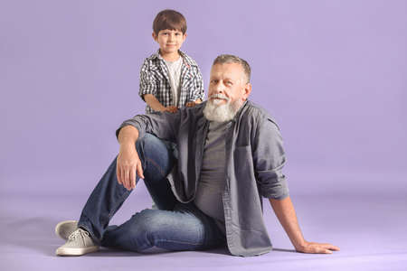 Cute little boy with grandfather on color backgroundの写真素材